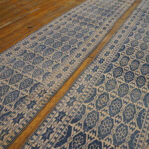 Two parallel blue and tan patterned runners with a distressed look resting on wood flooring.
