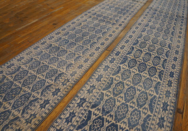 Two parallel blue and tan patterned runners with a distressed look resting on wood flooring.