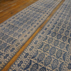 Two distressed blue and cream patterned runner rugs laid out on glossy wood flooring.