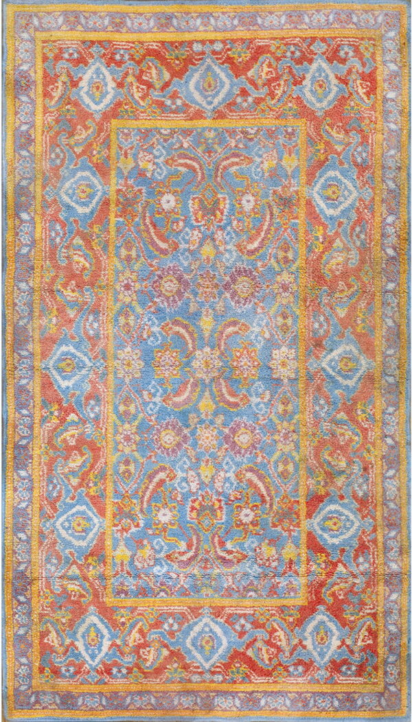 Distressed traditional rug with complex medallion and borders in contrasting blue, coral, and yellow.