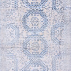 A rectangular low-pile rug with faded blue geometric octagonal patterns is laid on polished wood flooring.