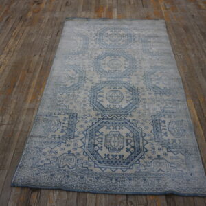 Blue and white geometric pattern rug with visible distressing rests on worn, wide wooden floorboards.