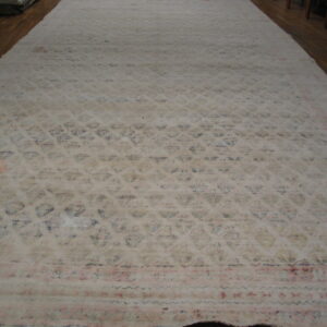 An oversized, faded cream rug with subtle blue and pink floral patterns covers dark wood floor.