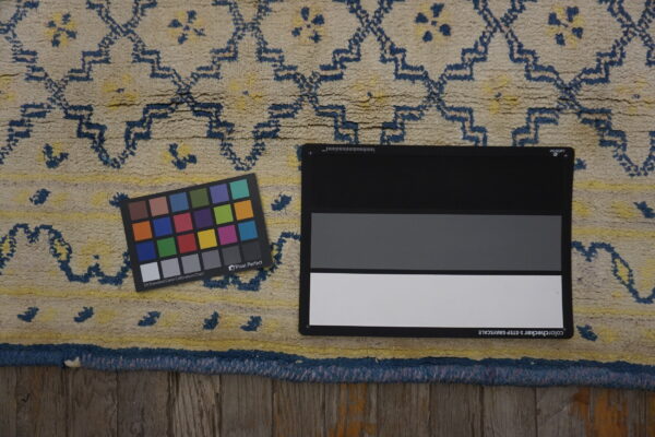 Close-up of a textured cream and dark blue geometric rug on wood, including calibration tools.