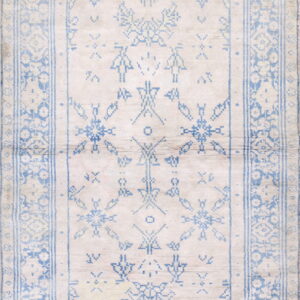 Ivory rug featuring a complex geometric and tribal pattern defined by fading light blue outlines and borders.