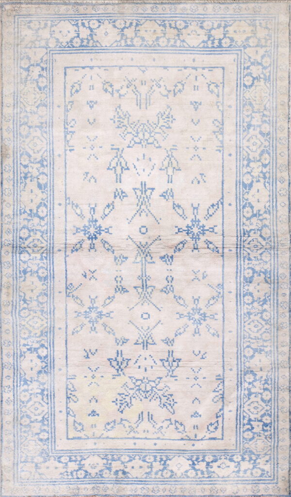 Ivory rug featuring a complex geometric and tribal pattern defined by fading light blue outlines and borders.