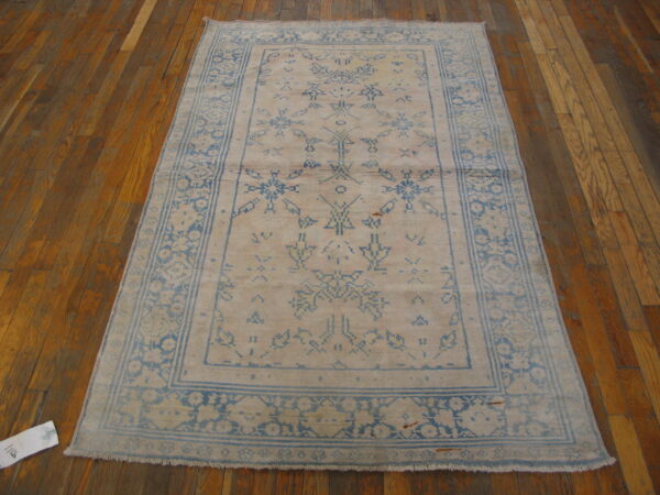 Light blue and tan distressed rug featuring a central medallion and multiple borders on glossy wood floors.