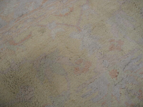 Shaggy rug surface detail with an abstract pattern of cream, pale pink, and soft gray colors.
