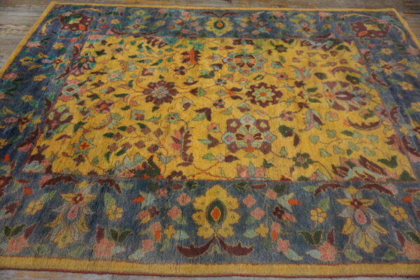 Colorful high-pile rug with a detailed yellow floral field and a contrasting blue patterned border on wood floor.