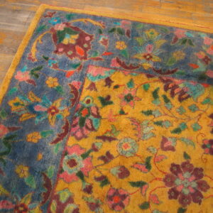 Multicolored high-pile rug corner featuring gold and blue grounds with dense floral designs on wood flooring.