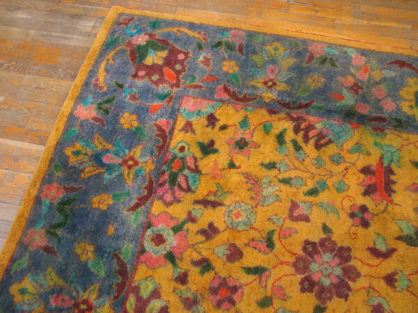 Multicolored high-pile rug corner featuring gold and blue grounds with dense floral designs on wood flooring.