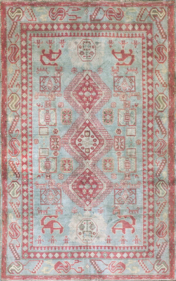Muted blue area rug covered in traditional geometric red motifs, centered by large diamond medallions.