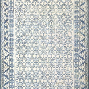 Ivory rug with a repeating distressed blue floral pattern enclosed by multiple dark blue borders.