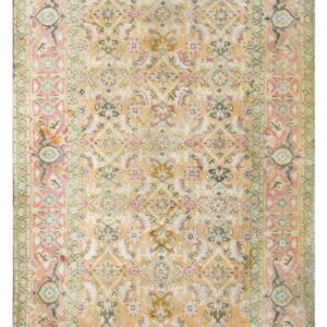 A distressed traditional rug featuring an apricot field with dusty pink, sage green, and blue floral motifs.