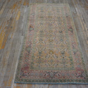 Faded traditional runner in apricot, pink, and green rests on distressed gray and yellow hardwood flooring.
