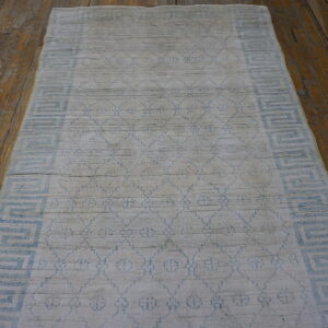 Light gray and blue geometric runner rug with high pile on a rustic hardwood floor.