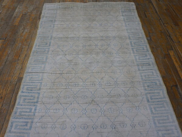 Light gray and blue geometric runner rug with high pile on a rustic hardwood floor.