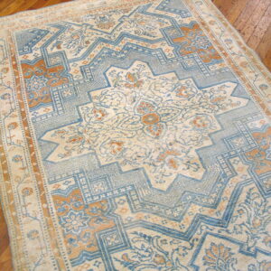 Light blue, beige, and terracotta geometric medallion rug covering a polished hardwood floor.