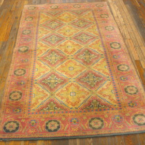 Yellow, pink, and blue patterned rug featuring geometric diamonds and floral medallions resting on distressed wood flooring.