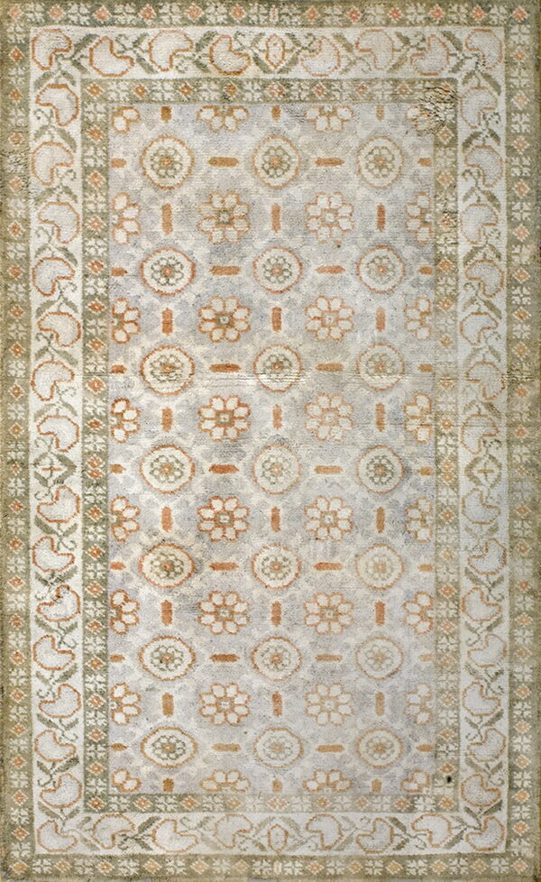Distressed low-pile rug featuring light gray, orange, and sage stylized floral medallions and wide borders.