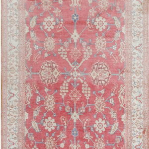 Rectangular low-pile rug featuring a coral field with faded ivory and pale blue intricate floral patterns.
