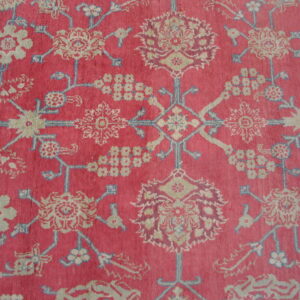 Deep pink rug detail featuring intricate stylized floral patterns in beige, light blue, and burgundy.