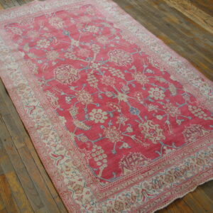 Rectangular pink and cream traditional rug with a detailed floral pattern on wide wood floorboards.