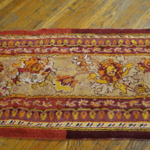 A runner rug with red, gold, and maroon floral and medallion patterns rests on wood flooring.