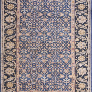 Ornate rug with a deep blue field and beige floral motifs bordered by large stylized flowers.