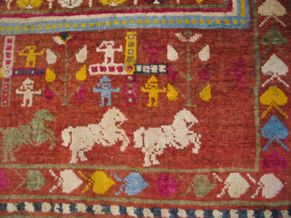 High-pile red rug detail showing white, blue, and yellow stylized figures and green and white horses.