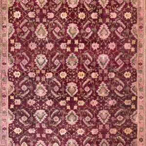 Burgundy rug with blush pink and sage green floral motifs lies centered on wide, light wood flooring.
