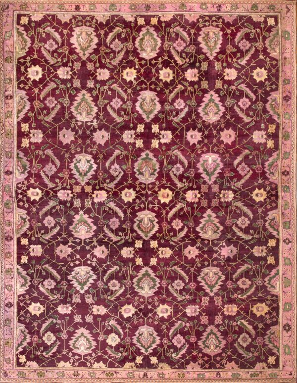 Burgundy rug with blush pink and sage green floral motifs lies centered on wide, light wood flooring.