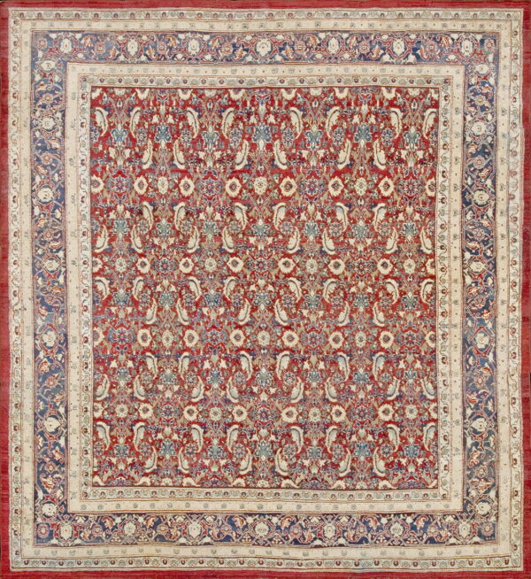 Red and navy traditional rug with dense all-over pattern and wide cream ornamental borders.
