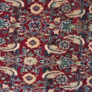 Distressed high-pile rug detail showing floral and curvilinear designs in burgundy, tan, blue, and green.