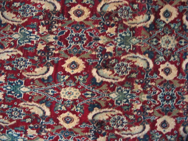 Distressed high-pile rug detail showing floral and curvilinear designs in burgundy, tan, blue, and green.