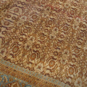 Beige rug field with an all-over intricate brown and rust floral pattern and a contrasting teal border.