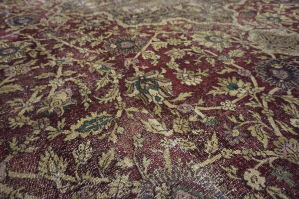 The low-pile rug features a distressed maroon background with an intricate faded gold and green floral pattern.