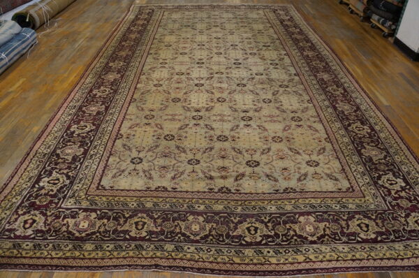 Large traditional rug with a pale green field and maroon border on light wood floors.