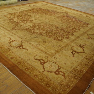 Ornate gold and rust patterned rug with multiple borders displayed on wide plank wooden flooring.