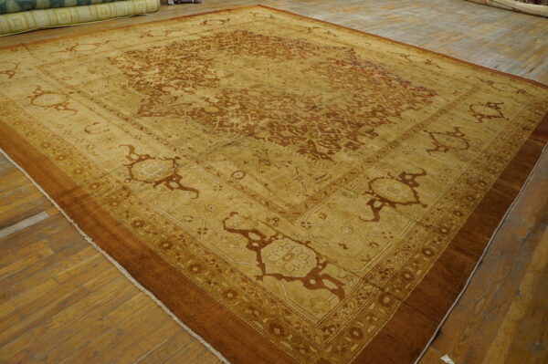 Ornate gold and rust patterned rug with multiple borders displayed on wide plank wooden flooring.