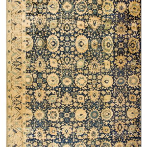 Dense blue rug pattern featuring stylized beige and blue floral motifs and a wide tan border.