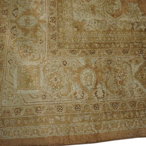 Detail of a traditional patterned rug corner showing multiple borders in muted beige and light brown.