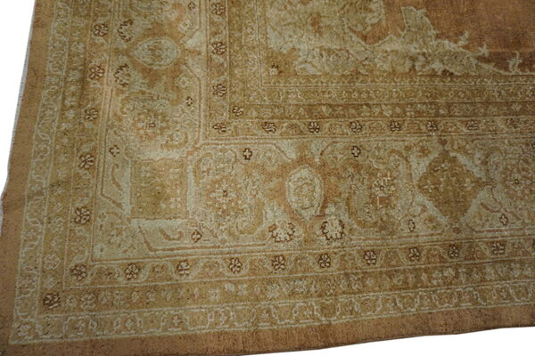 Detail of a traditional patterned rug corner showing multiple borders in muted beige and light brown.