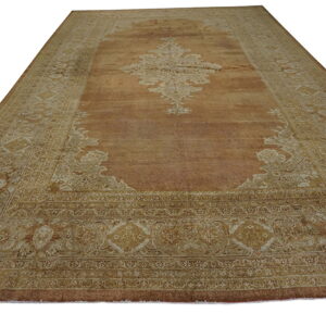 Large traditional rug featuring a copper field and elaborate tan and beige medallion and borders.