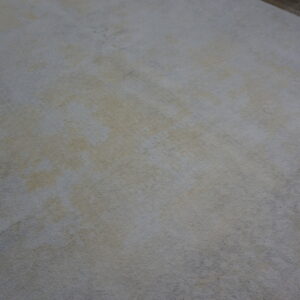 A light gray and cream distressed rug with subtle texture rests on dark brown wood plank flooring.