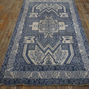 Indigo and cream rug featuring a central geometric medallion design lying on rustic orange-toned wood floorboards.