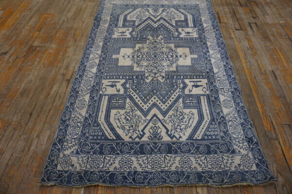 Indigo and cream rug featuring a central geometric medallion design lying on rustic orange-toned wood floorboards.