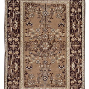 A rectangular rug in tan, cream, and dark brown with complex traditional motifs and contrasting borders.