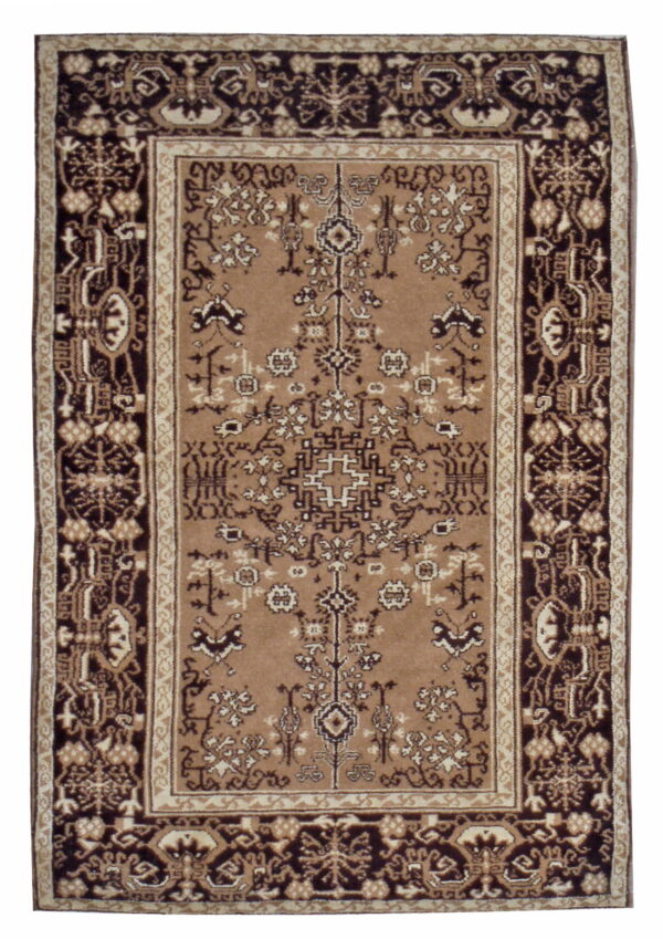 A rectangular rug in tan, cream, and dark brown with complex traditional motifs and contrasting borders.