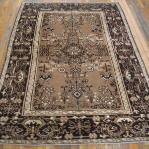 Rectangular brown rug featuring an intricate dark brown and tan traditional pattern on wood flooring.